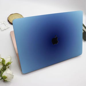 Puede incluir: Un ordenador portátil azul con un diseño degradado. El portátil tiene un logotipo de Apple plateado en la tapa.