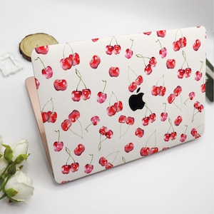 May include: A white laptop skin with a red cherry pattern. The skin is designed to fit a MacBook.