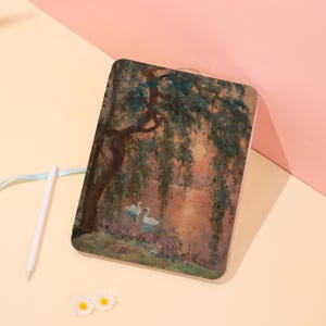 May include: A rectangular case featuring a painting of a serene waterscape with two swans, a weeping willow, and a sunset. The artwork is in shades of green, brown, and orange, with a light blue ribbon and a white stylus.