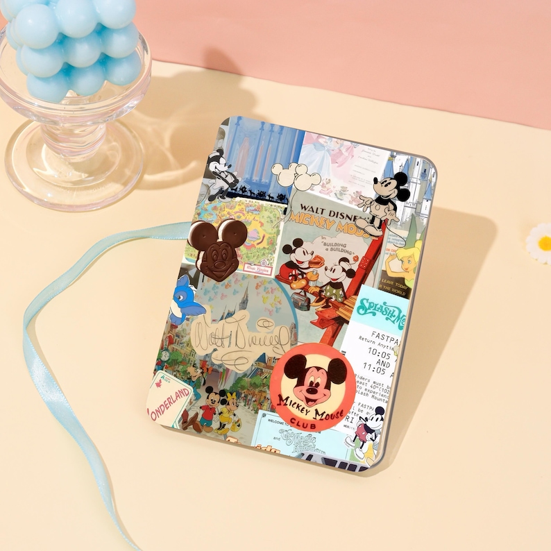 May include: A clear phone case featuring a collage of vintage Mickey Mouse imagery. The design includes various Mickey Mouse illustrations, logos, and text elements, with a circular Mickey Mouse Club logo. The case is on a light pink surface.