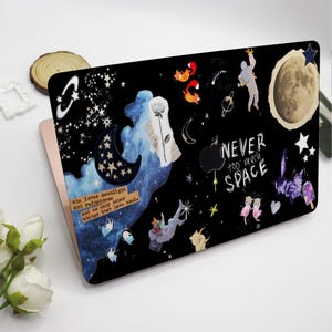 Op de afbeelding: Een zwarte laptop-skin met een galaxy-ontwerp met sterren, manen en andere hemellichamen. De skin bevat ook een citaat: "NEVER too much SPACE".