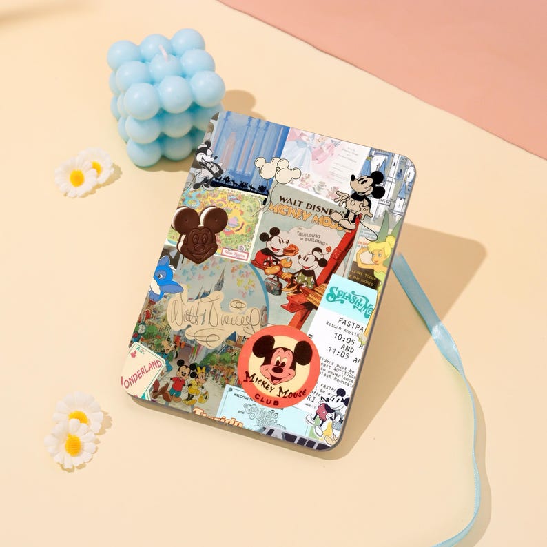 May include: A rectangular case with a collage of vintage Disney images, including Mickey Mouse, and the text "WALT DISNEY MICKEY MOUSE CLUB". The case has a light blue ribbon and is surrounded by a blue bubble candle and white daisy-shaped decorations.