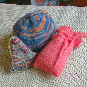 Puede incluir: Tres artículos de punto: un gorro a rayas azul y marrón, una bolsa rosa y una bolsa triangular multicolor.