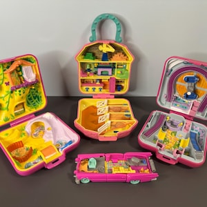 Op de afbeelding: Een verzameling vintage Polly Pocket speelsets in verschillende vormen en ontwerpen. De sets zijn open en onthullen miniatuurscènes met heldere kleuren, waaronder een huis, een schuur, een auto en een achtbaan. De sets zijn roze, geel en groen.