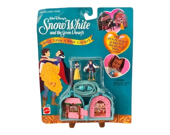 May include: A Snow White and the Seven Dwarfs Once Upon a Time Locket playset. The package includes a necklace with a locket that opens to reveal miniature figures of Snow White and the Prince. The package is teal and pink with illustrations of the characters.
