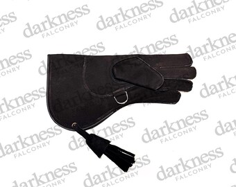 May include: Black falconry glove with a suede finish, featuring a D-ring and a tassel. The glove is designed for handling birds of prey. The word "darkness" is printed on the background.