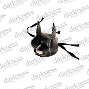 Peut inclure: Capuche en cuir noir avec des oreilles pointues et des coutures blanches. La capuche a une large ouverture et des liens noirs. Le mot "darkness" est répété en arrière-plan.
