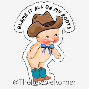 May include: A cartoon baby wearing a brown cowboy hat and blue boots. The baby is standing with its hands on its hips. The text "Blame it all on my roots" is written in a circle around the baby.