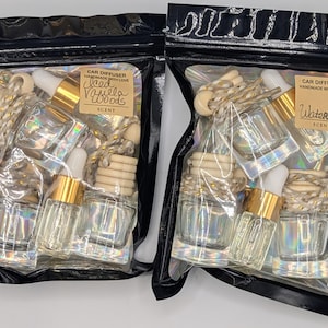 K&ouml;nnte beinhalten: Zwei schwarze Plastikt&uuml;ten gef&uuml;llt mit Auto-Lufterfrischern. Jede T&uuml;te enth&auml;lt kleine Glasflaschen mit goldfarbenen Deckeln, Holzperlen und einer Pipette. Eine T&uuml;te tr&auml;gt die Aufschrift "Iced Vanilla Woods", die andere "Watermelon".