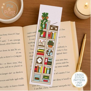 Op de afbeelding: Kruissteekpatroon voor een bladwijzer met een boekenkast met boeken, planten, kaarsen en een globe. De bladwijzer is wit met bruine, groene, rode, gele en blauwe accenten. De tekst "CROSS STITCH PATTERN - PDF ONLY" staat in de rechterbenedenhoek.