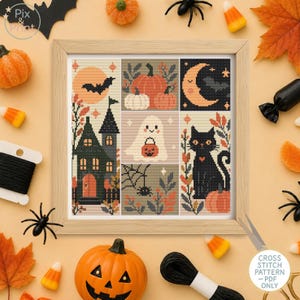 May include: A framed cross stitch sampler featuring a grid of six Halloween-themed illustrations including a haunted house, a ghost holding a pumpkin bucket, a black cat, a crescent moon, pumpkins, and a spider web with a spider on a light background.