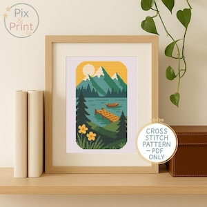 Op de afbeelding: Ingelijst kruissteekpatroon met een landschap met bergen, een meer en een boot. Het kunstwerk bevat een gele zon, groene bomen en gele bloemen. De lijst is lichtbruin en de tekst "CROSS STITCH PATTERN - PDF ONLY" is zichtbaar.
