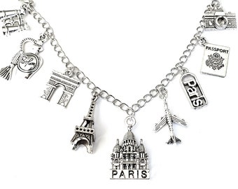 Könnte beinhalten: Silbernes Charm-Armband mit verschiedenen Pariser Motiven, darunter der Eiffelturm, der Arc de Triomphe, ein Parfümflakon, ein Reisepass, ein Flugzeug und ein Gebäude mit der Aufschrift "Paris".