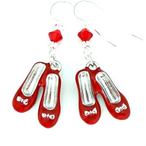 May include: Red and silver dangle earrings featuring a pair of red shoes with silver bows. The earrings are accented with red crystal beads.