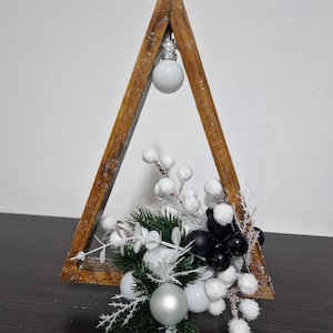 Scandinavische kerstdecoratie – houten driehoekige lijst met zwart-witte ornamenten en sneeuwaccenten
