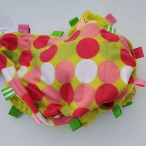 May include: A green and pink polka dot baby blanket with green and white ribbon tags.