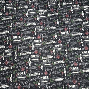 Puede incluir: Tela negra con un patrón repetido de temática navideña. El diseño incluye la palabra "NOEL", bastones de caramelo, adornos, acebo y las frases "Happy Christmas!" y "Let it snow, Holiday!"