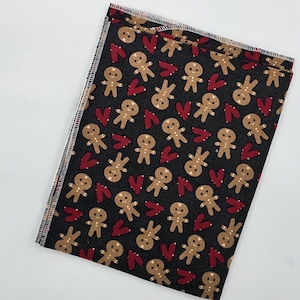 May include: Black fabric with a repeating pattern of gingerbread men and red hearts.