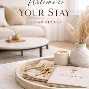 May include: A coffee table with a marble top features a tray with keys, a welcome guide, and a lit candle. A vase with dried pampas grass and the text "Welcome to YOUR STAY 5-STAR AIRBNB" are also visible.