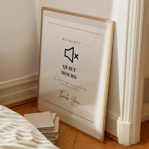 May include: A framed print with a gold-colored frame, leaning against a wall. The print has the words "NO PARTY" at the top, a speaker icon with an X, and the words "QUIET HOURS" below. The text "10 PM 7 AM PLEASE BE RESPECTFUL" and "Thank You" are also visible.