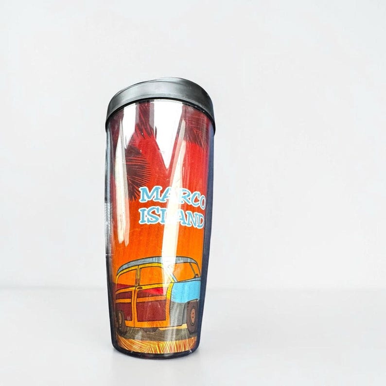 A tall, clear tumbler with a printed design on it, featuring a car and palm trees.