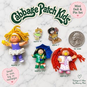May include: A Cabbage Patch Kids mini doll and pin set featuring three small dolls and two pins. The dolls have yarn hair and outfits, with sizes labelled as approximately 5 cm and 3.8 cm. The pins are approximately 1.9 cm and 2.5 cm tall.