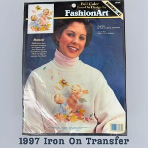 The image is a 1997 Iron On Transfer package featuring a smiling woman with a white sweater adorned with angel designs.