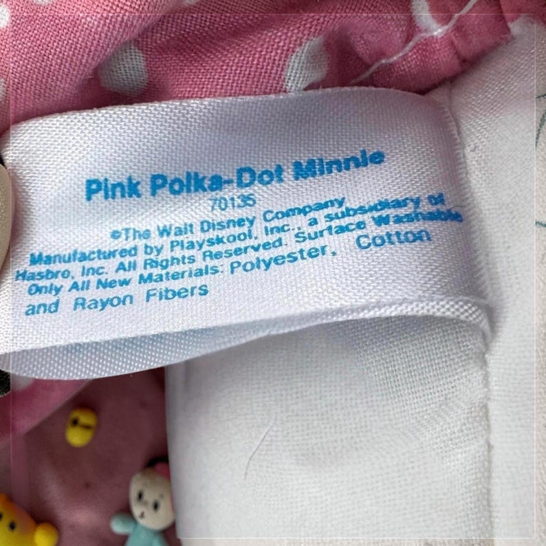 a close-up of a label on a pink fabric, with a small amount of text printed on it.