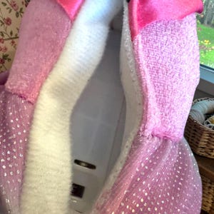 A close-up view of a pink and white fluffy fabric, possibly a robe or blanket, with a white electrical outlet visible in the center.