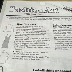 The image is a page from a fashion art book, featuring various fashion items such as dresses and shirts, along with instructions on how to transfer patterns onto fabric.