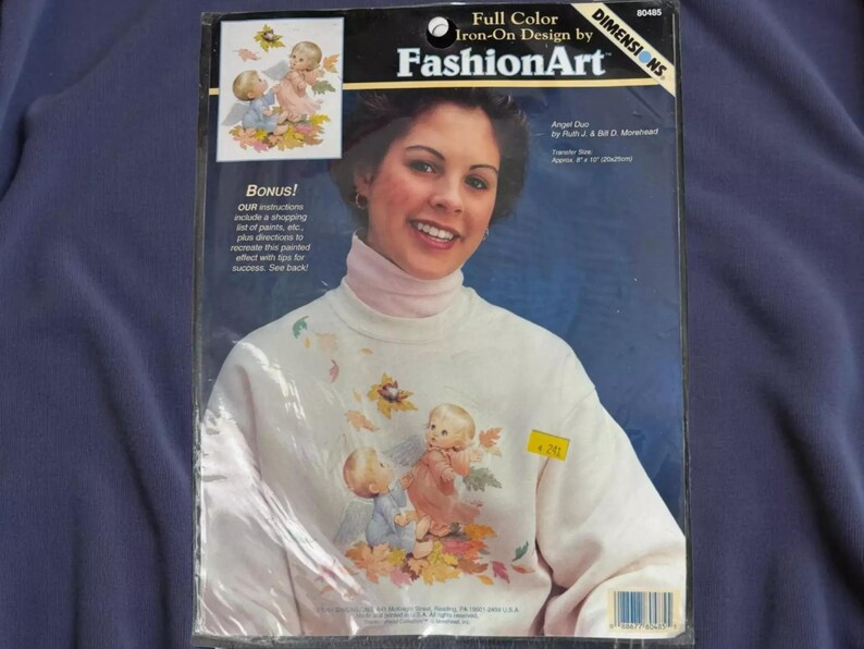 The image is a package for Iron-On Design by FashionArt, featuring a smiling woman with a white sweater adorned with a design of cherubs and leaves.