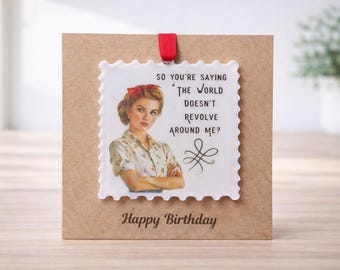 May include: A birthday card with a vintage-style image of a woman with a red bow in her hair. The card has the text "So you're saying the world doesn't revolve around me?" and "Happy Birthday" printed on it.