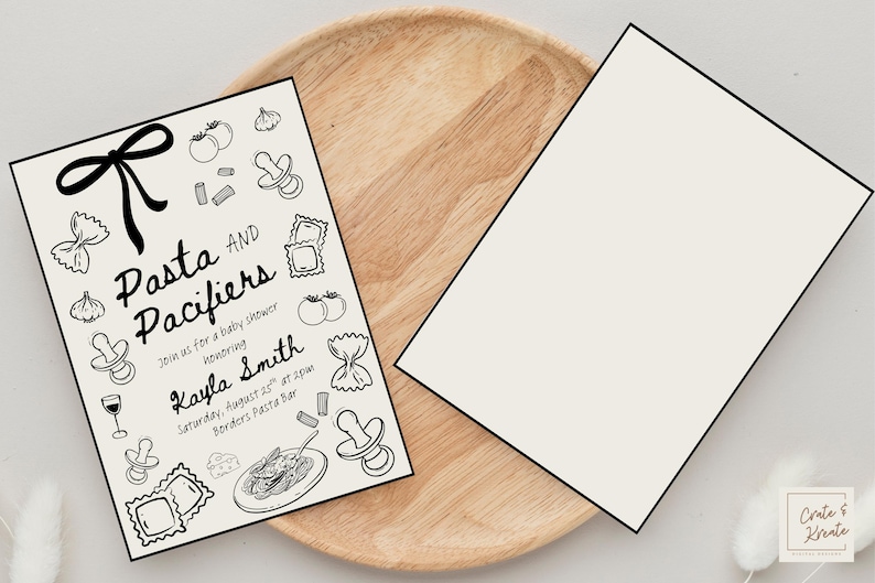 Puede incluir: Dos invitaciones para un baby shower, una con el texto "Pasta and Pacifiers" e ilustraciones de formas de pasta, chupetes y tomates. La otra invitaci&oacute;n est&aacute; en blanco. Ambas est&aacute;n sobre una bandeja de madera.