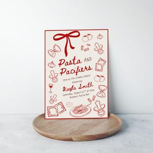 Puede incluir: Una invitaci&oacute;n a un baby shower con un borde rojo y un fondo crema. La invitaci&oacute;n presenta ilustraciones rojas de pasta, chupetes y otros art&iacute;culos para beb&eacute;s. El texto dice "Pasta and Pacifiers" e incluye los detalles del evento.