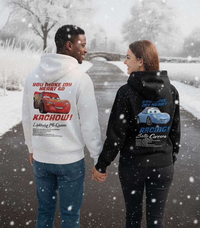 May include: Two people wearing matching hoodies, walking on a snowy path. One hoodie is white with a red Lightning McQueen graphic and the text "YOU MAKE MY HEART GO KACHOW!". The other is black with a blue Sally Carrera graphic and the text "YOU LIVE MY HEART RACING!".