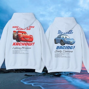 May include: Two white hooded sweatshirts with cartoon car graphics. One features Lightning McQueen with "Kachow!" and the text "You stole my heart go". The other displays Sally Carrera with "Racing!" and "You are my heart".