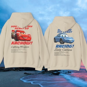 May include: Two beige hoodies with car graphics. One features Lightning McQueen with "Kachow!" and "You stole my heart go" text. The other displays Sally Carrera with "Racing!" and "You are my heart" text. Both have additional text below the car graphics.