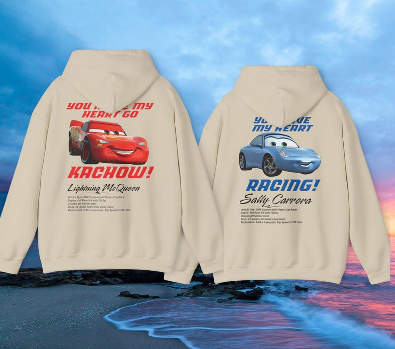 May include: Two beige hoodies with car graphics. One features Lightning McQueen with "Kachow!" and "You stole my heart go" text. The other displays Sally Carrera with "Racing!" and "You are my heart" text. Both have additional text below the car graphics.