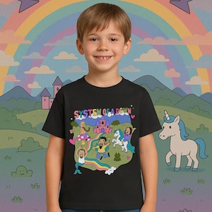 May include: A black t-shirt featuring a cartoon illustration of a band performing in a fantasy setting. The illustration includes a castle, a unicorn, a frog, and a rainbow. The text "SYSTEM OF A DOWN" is printed on the shirt.