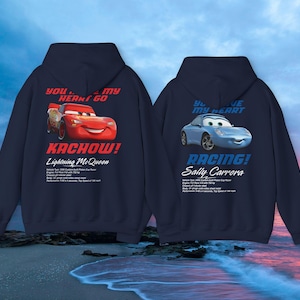May include: Two navy blue hooded sweatshirts featuring characters from the movie Cars. One displays Lightning McQueen with the text "Kachow!" and the other features Sally Carrera with the text "Racing!"