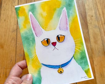 May include: Watercolour painting of a white cat with orange eyes, a pink nose, and a blue collar with a gold bell. The background is a blend of yellow and green. The artist's signature is in the bottom right corner.