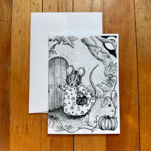 May include: A black and white illustration of a mouse in a pumpkin-patterned outfit, holding a bag, standing in front of a wooden door. A white envelope and card are on a wooden surface. The scene includes a pumpkin, leaves, and a tree.