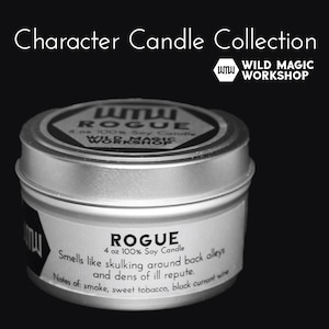 May include: A silver tin candle with a black label that reads "ROGUE 4 oz 100% Soy Candle" and "Smells like skulking around back alleys and dens of ill repute. Notes of: smoke, sweet tobacco, black currant wine". The label also features the text "WILD MAGIC WORKSHOP".