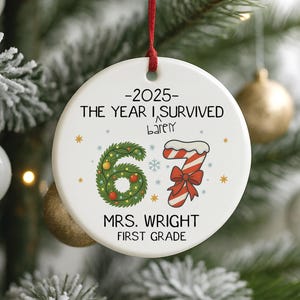 May include: A white ceramic Christmas ornament with a red ribbon. The ornament features the text "-2025- THE YEAR I SURVIVED barely" and "67" in a wreath design, a candy cane, and "MRS. WRIGHT FIRST GRADE".