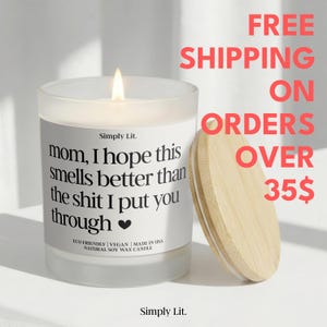 May include: A white glass candle with a wooden lid. The candle has a label with the text "mom, I hope this smells better than the shit I put you through." The candle is made with natural soy wax and is eco-friendly and vegan.