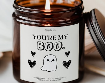 May include: A lit soy wax candle in a brown glass jar with a black lid. The label reads "You're My Boo" with a ghost and heart graphics. The candle is eco-friendly, vegan, and made in the USA.