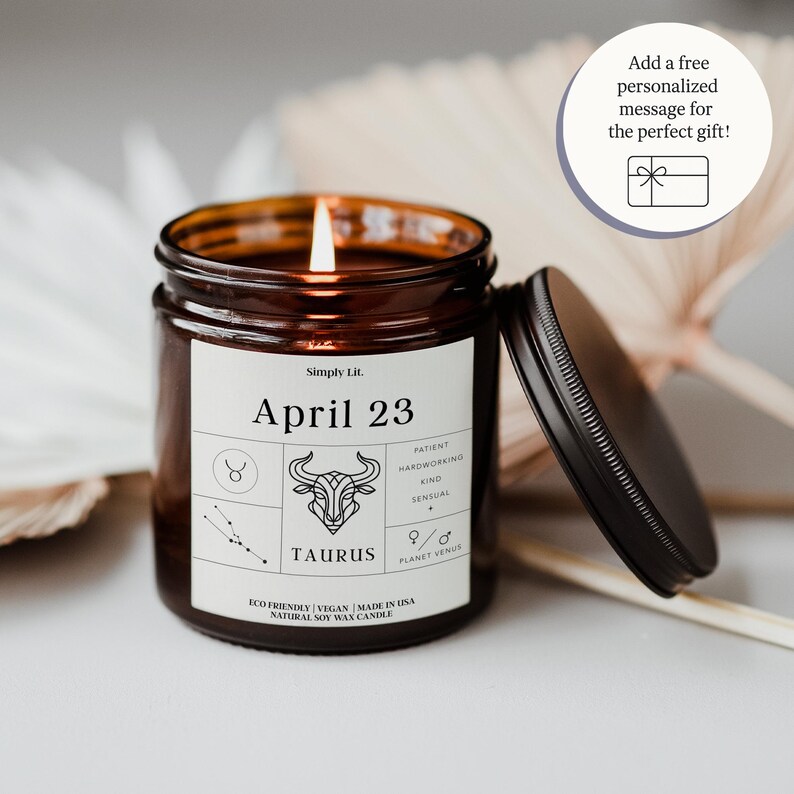 K&ouml;nnte beinhalten: Eine brennende braune Glas-Kerze mit schwarzem Deckel, mit einem Etikett mit dem Text "April 23" und "Taurus". Das Etikett enth&auml;lt auch Tierkreiszeichen und die W&ouml;rter "Patient, Hardworking, Kind, Sensual". Die Kerze ist umweltfreundlich und aus nat&uuml;rlichem Sojawachs hergestellt.