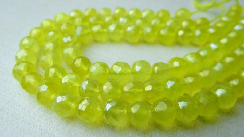 May include: A strand of faceted, round beads in a vibrant, translucent yellow-green color. The beads have a polished, glossy finish, and are strung together on a thin, light-yellow cord. The beads are approximately 8mm in diameter.