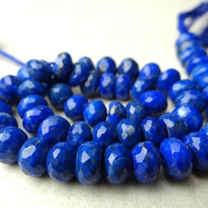 Pu&ograve; includere: Una collana di perline sfaccettate di lapislazzuli blu intenso. Le perline sono di un blu ricco e saturo con una superficie lucida e riflettente. Il filo &egrave; anch'esso blu, con un nappa all'estremit&agrave;. Le perline sono disposte a cerchio.