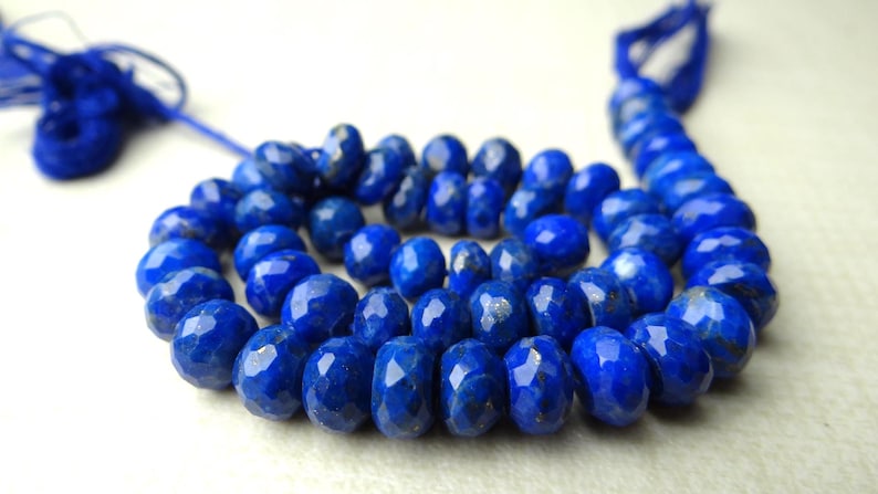 Pu&ograve; includere: Una collana di perline sfaccettate di lapislazzuli blu intenso. Le perline sono di un blu ricco e saturo con una superficie lucida e riflettente. Il filo &egrave; anch'esso blu, con un nappa all'estremit&agrave;. Le perline sono disposte a cerchio.